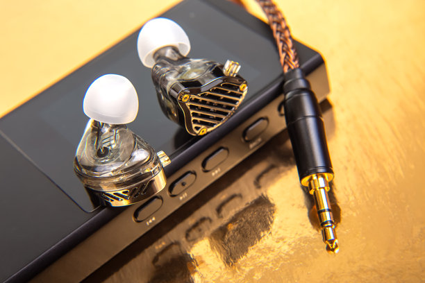 带编织线缆的有线耳塞放置在黑色音频设备上，背景为光滑的金色。非常适合音乐爱好者、科技爱好者和产品拍摄。高分辨率照片。图片下载