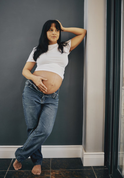 自信的孕妇穿着休闲白衬衫和牛仔裤图片下载