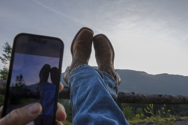 牧场主在日出时拍摄脚放在栅栏上的照片图片下载