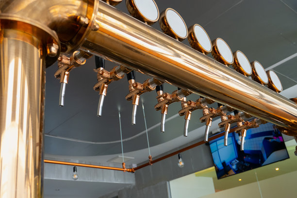 酒吧里的复古啤酒龙头，一排不同的啤酒龙头在酒吧里整齐排列，从下方看去。图片下载