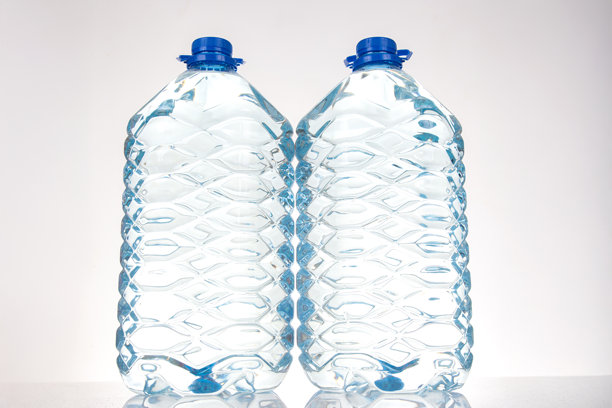 两个带蓝色盖子的塑料水瓶，具有独特的波浪设计，孤立在白色背景上。适合健康、补水或环保产品的库存图片。图片下载