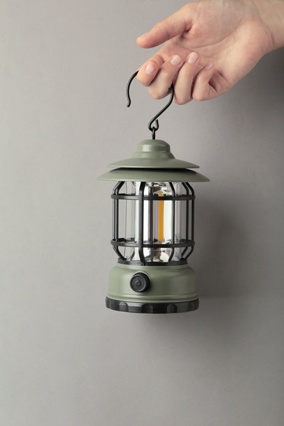 手握灯笼在灰色背景上。露营。竖版照片图片下载