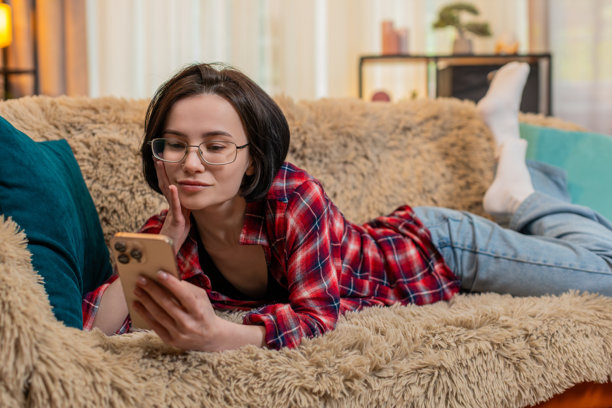 女人在智能手机上浏览旅行照片，微笑着回忆假期的美好时光。图片下载