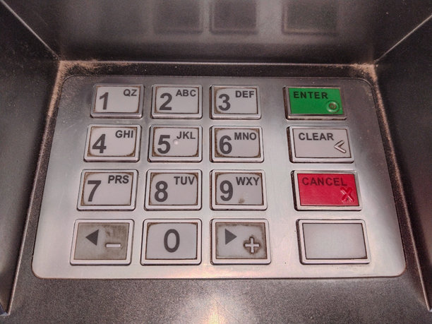 自动取款机的特写照片，显示完整的键盘布局，用于安全的银行交易和公共场所的数字取款。图片下载