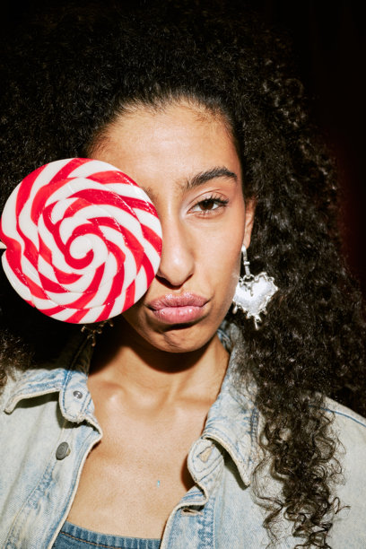 中东年轻女性在照片亭中摆姿势，手持棒棒糖的肖像图片下载