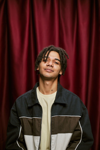 年轻黑人男子在红色幕布前的照片亭中微笑的肖像图片下载