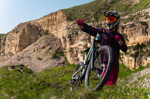户外骑行的男子骑着山地自行车。男性游客在山中的草地小径上骑自行车，佩戴头盔和护目镜。运动、户外活动和自然概念。图片下载