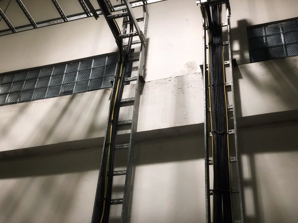 这张图片展示了一个房间内的垂直和水平电缆托盘系统，可能是一个工厂或仓库。图片下载