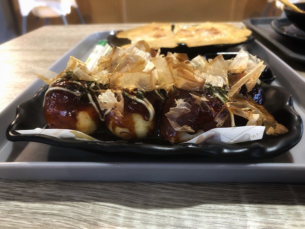 这张图片展示了盛在椭圆形黑色盘子上的章鱼烧。图片下载