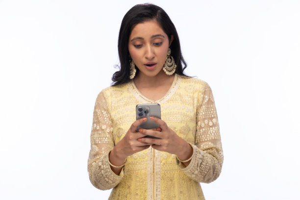 穿着传统服装的美丽女性在白色背景下庆祝排灯节，使用手机拍照的照片图片下载