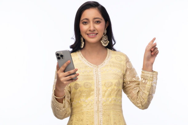 穿着传统服装的美丽女性在白色背景下庆祝排灯节，使用手机拍照的照片图片下载