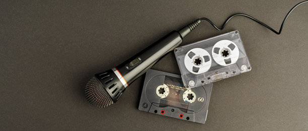 黑色专业卡拉OK麦克风和两盘复古音频磁带，背景为黑色，留有文字空间。适合用作横幅的照片。图片下载