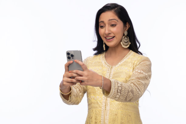 穿着传统服装的美丽女性在白色背景下庆祝排灯节，使用手机拍照的照片图片下载