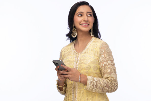 穿着传统服装的美丽女性在白色背景下庆祝排灯节，使用手机拍照的照片图片下载