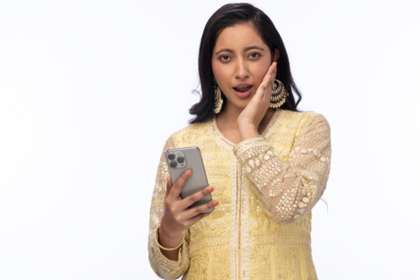 穿着传统服装的美丽女性在白色背景下庆祝排灯节，使用手机拍照的照片图片下载