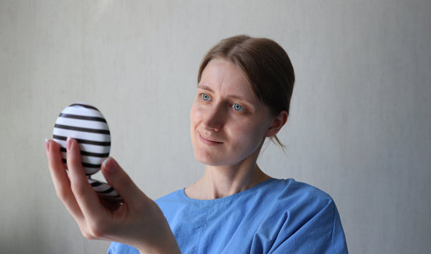 一位女性正在看着圆形口袋镜子。白人女性，金色头发，蓝色眼睛，穿着衬衫，微微微笑。照片。图片下载