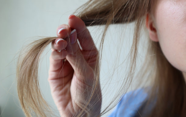 女性手握住头发。微距照片。浅金色头发。一束头发。毛发学，美容学，健康与护理。图片下载