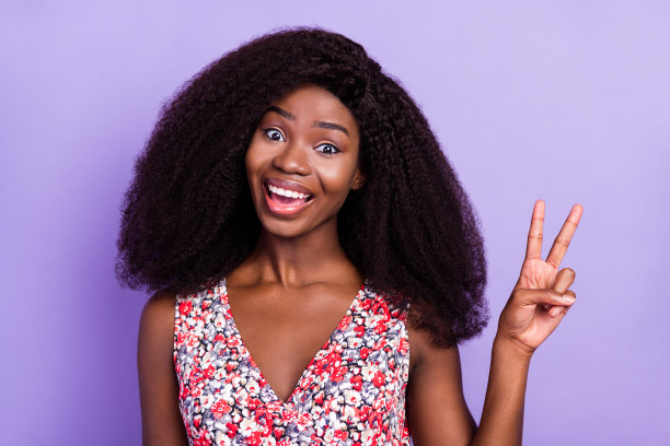 在淡紫色背景上微笑着做出V字手势的快乐人像照片图片下载