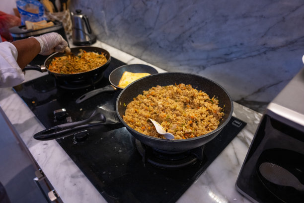 特写照片显示一位厨师在厨房中用热锅翻炒素食蛋面。图片下载