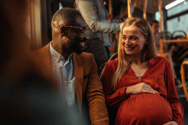 一位年轻的黑人男性和一位孕妇坐在公交车上图片下载