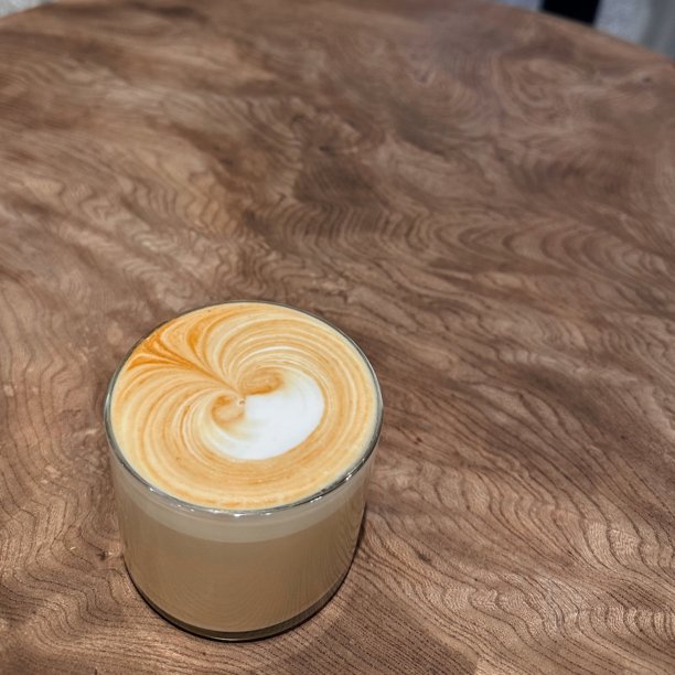 一杯精美的拿铁，上面装饰着丰富浓郁的浓缩咖啡和奶泡艺术。非常适合与咖啡相关的项目，这张图片捕捉了经典咖啡馆体验的温暖和诱人氛围。图片下载