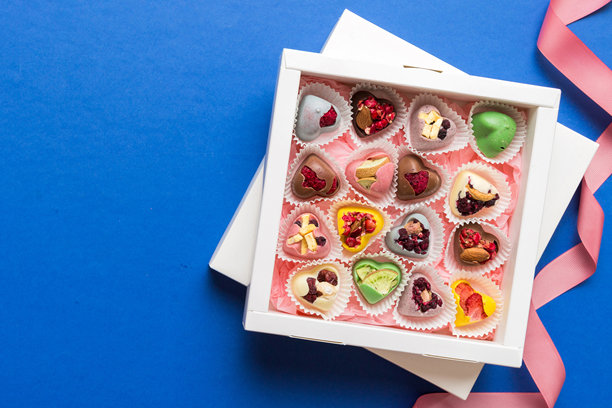 节日构图：甜美的糖果，带有蝴蝶结的礼品盒和巧克力心形，照片模板，背景。俯视图，彩色背景上留有空白空间。图片下载