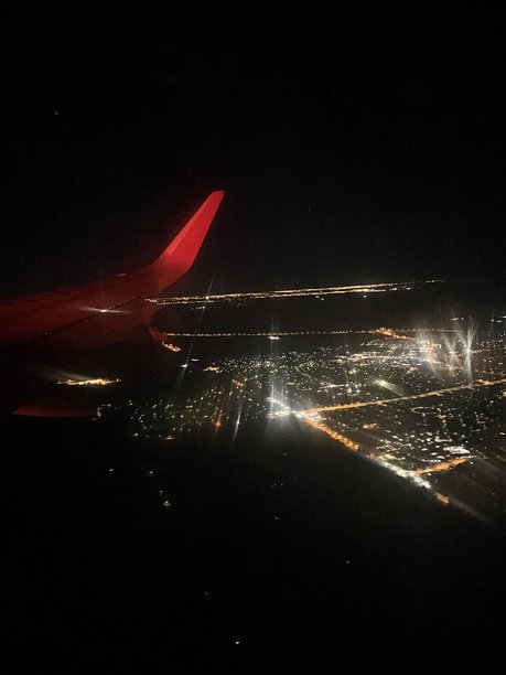 这张图片捕捉了从飞机窗座看到的夜景，机翼上可见的飞机注册号表明了这一点。图片下载