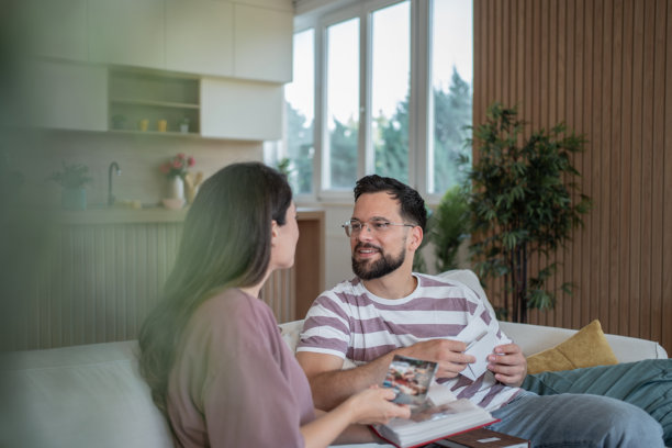 一对情侣坐在沙发上观看旧照片，回忆一起度过的快乐时光图片下载