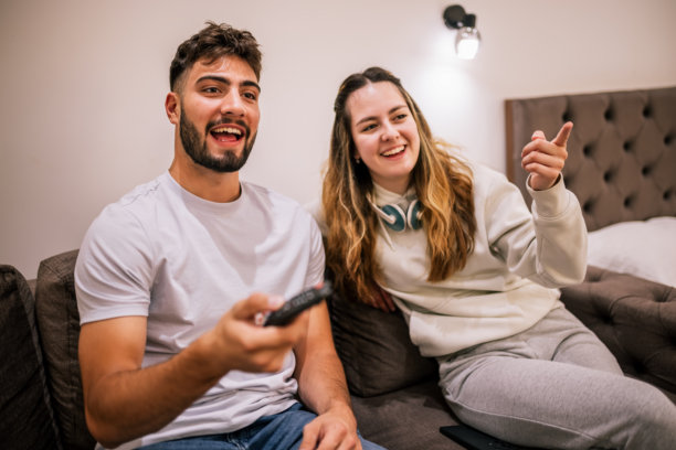 年轻情侣在酒店房间的沙发上看电视图片下载