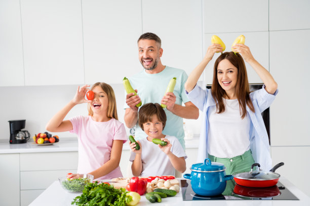 孩子们和父母在白色厨房里一起做饭，玩弄新鲜蔬菜，欢笑嬉闹的照片肖像图片下载
