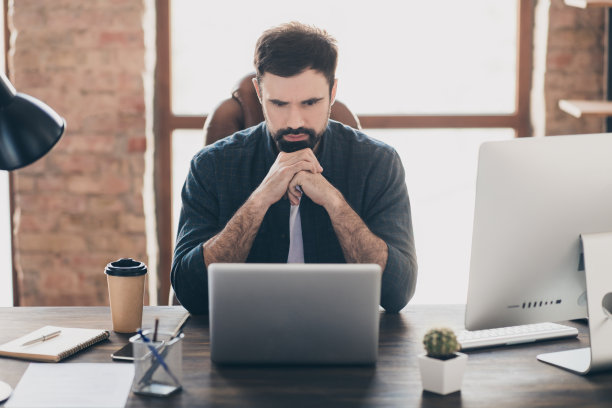 在办公室使用笔记本电脑浏览互联网的沉思工作者的照片肖像图片下载