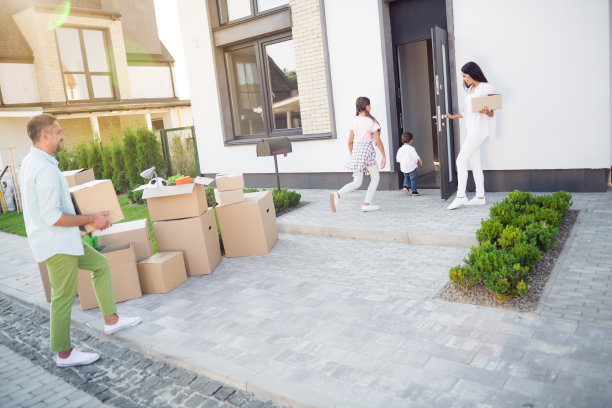 快乐微笑的家庭搬家全景照片，爸爸妈妈搬着箱子，女孩和小男孩走进新家。图片下载