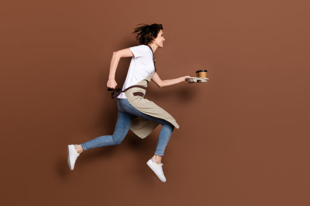 全身侧面照片，快乐的咖啡师奔跑着，手中拿着咖啡，背景为棕色，留有空白空间。图片下载