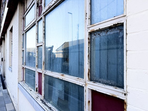 一扇原始复古风格的艺术装饰奶油色和红色窗户，映照出诺森伯兰郡布莱斯的城市建筑。图片下载