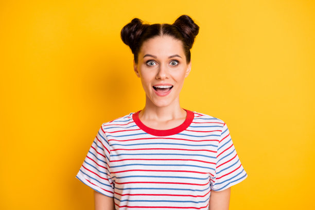 穿着条纹服装、张嘴大眼的搞笑惊讶年轻女士的照片，背景为黄色。图片下载