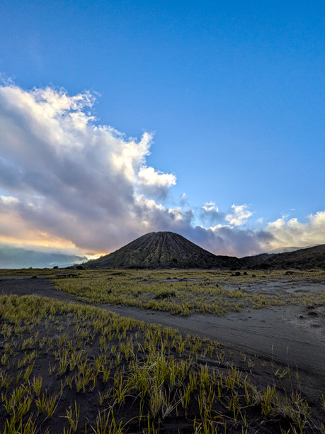 一幅美丽的垂直山景照片，背景是戏剧性的蓝天，云朵呈现出大块的白色和灰色。这个场景展现了环境的强大和壮丽。图片下载