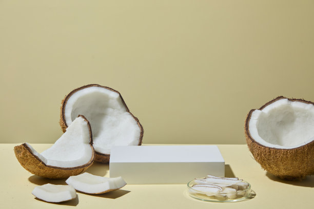椰子放置在米色背景的空讲台旁。照片将生椰子与加工美容产品联系起来，展示了自然和成品的两种形式。留有展示产品的空间。图片下载