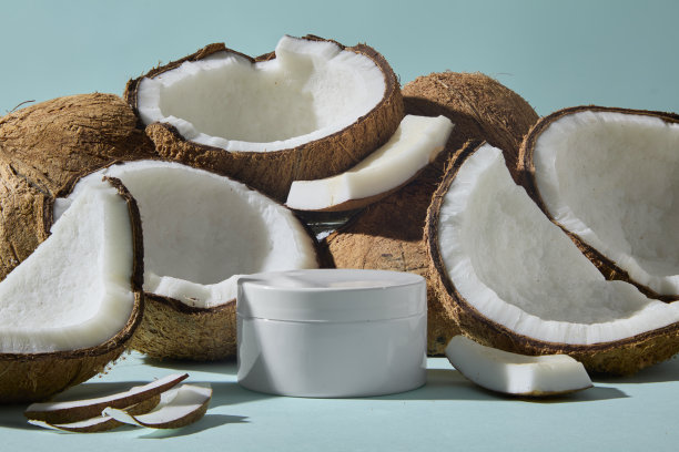 多个椰子的横向框架，配有白色罐子的样品。图片暗示了椰子基底的护肤霜或身体磨砂膏，适合日常肌肤护理。广告照片图片下载