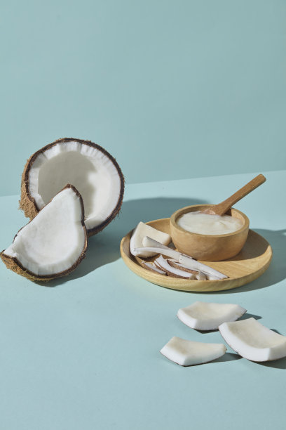 在蓝色背景上，垂直摆放的椰子、木勺和装饰的清洁碗。这张图片突出了椰子作为天然水疗和身体护理程序的核心成分。图片下载