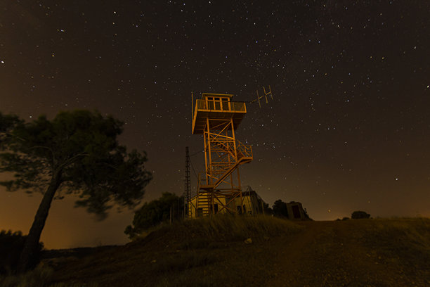 在宁静的山顶上，仰望星空，瞭望塔下是布满星星的晴朗夜空图片下载