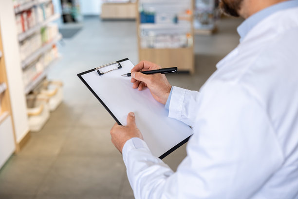 穿着实验室外套的男子在做笔记的特写照片图片下载