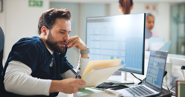 医院里拿着文件夹的男医生或接电话，更新病人预约或医疗信息。医疗保健，专家或在前台确认转诊或帮助安排日程。图片下载