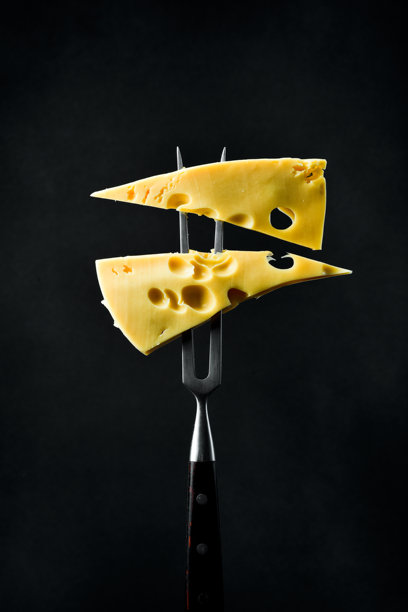 两块马斯达姆奶酪放在金属叉上。黑色背景，竖版照片。图片下载