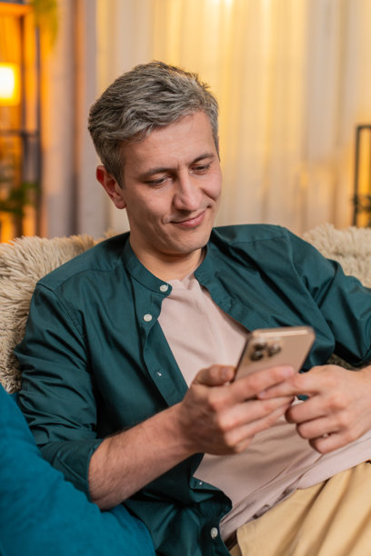 年轻男子微笑着在智能手机上浏览旧家族照片，享受温馨的怀旧时刻图片下载