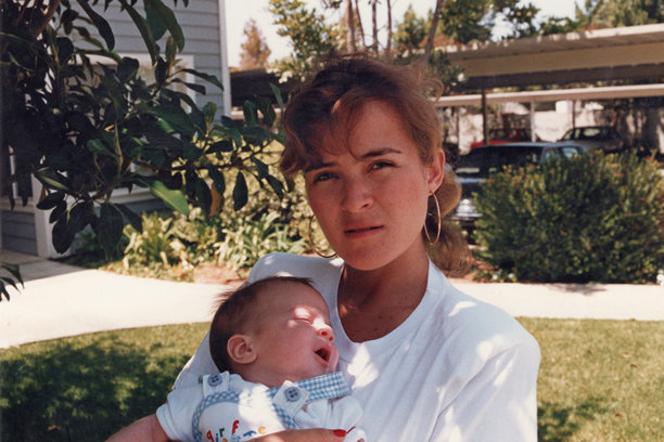 1980年代拍摄的照片：年轻女性抱着孩子，面向镜头。图片下载