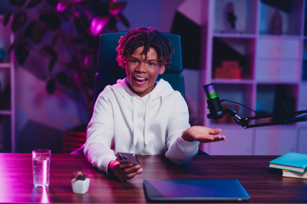 年轻男性游戏玩家和视频博主在时尚环境中使用麦克风和电脑制作在线直播内容图片下载