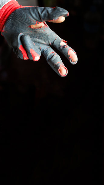 一张强烈的竖拍，捕捉到一只手上的破损手套，两个手指伸出，背景是鲜明的黑色。这张图片深刻地表现了贫困和艰辛。图片下载