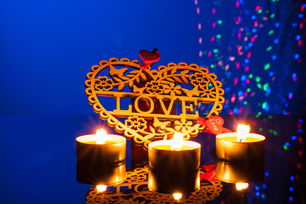 浪漫的蜡烛在照片中闪烁，环绕着一个装饰性的木制心形物件图片下载