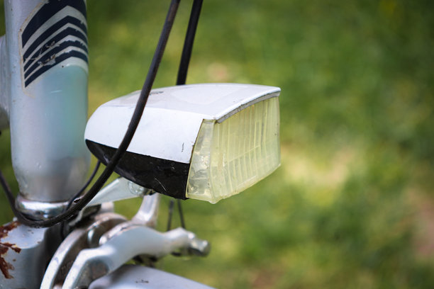 一盏挂在车把上的旧自行车前灯讲述着悠久的历史和许多旅程。它磨损的外观为照片增添了一种复古、怀旧和魅力的感觉。这是一幅完美的图像，展现了复古、过去时代和自行车的主题。图片下载