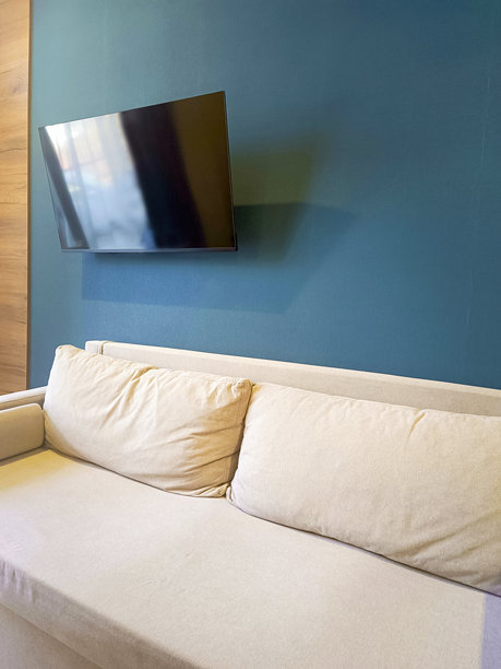 现代室内的一部分。墙边的沙发和悬挂的电视。特写，竖拍照片。图片下载